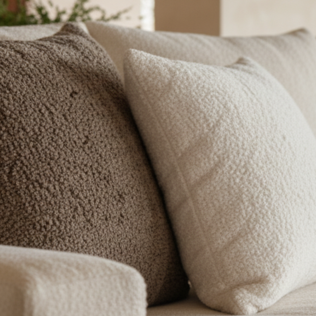 Two textured pillows, one brown and one beige, on a sofa.