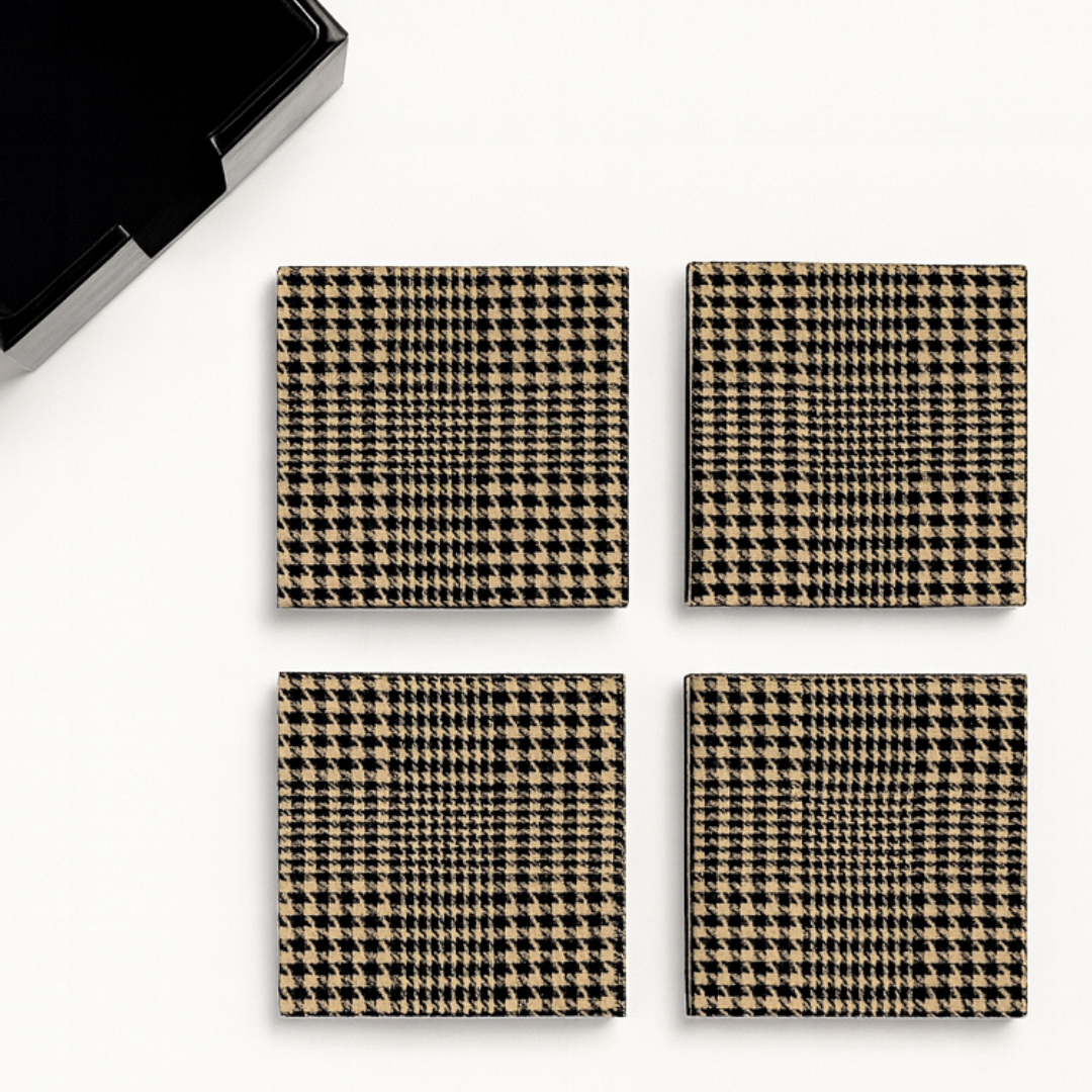 Four houndstooth patterned coasters on a white surface with a phone in the corner.