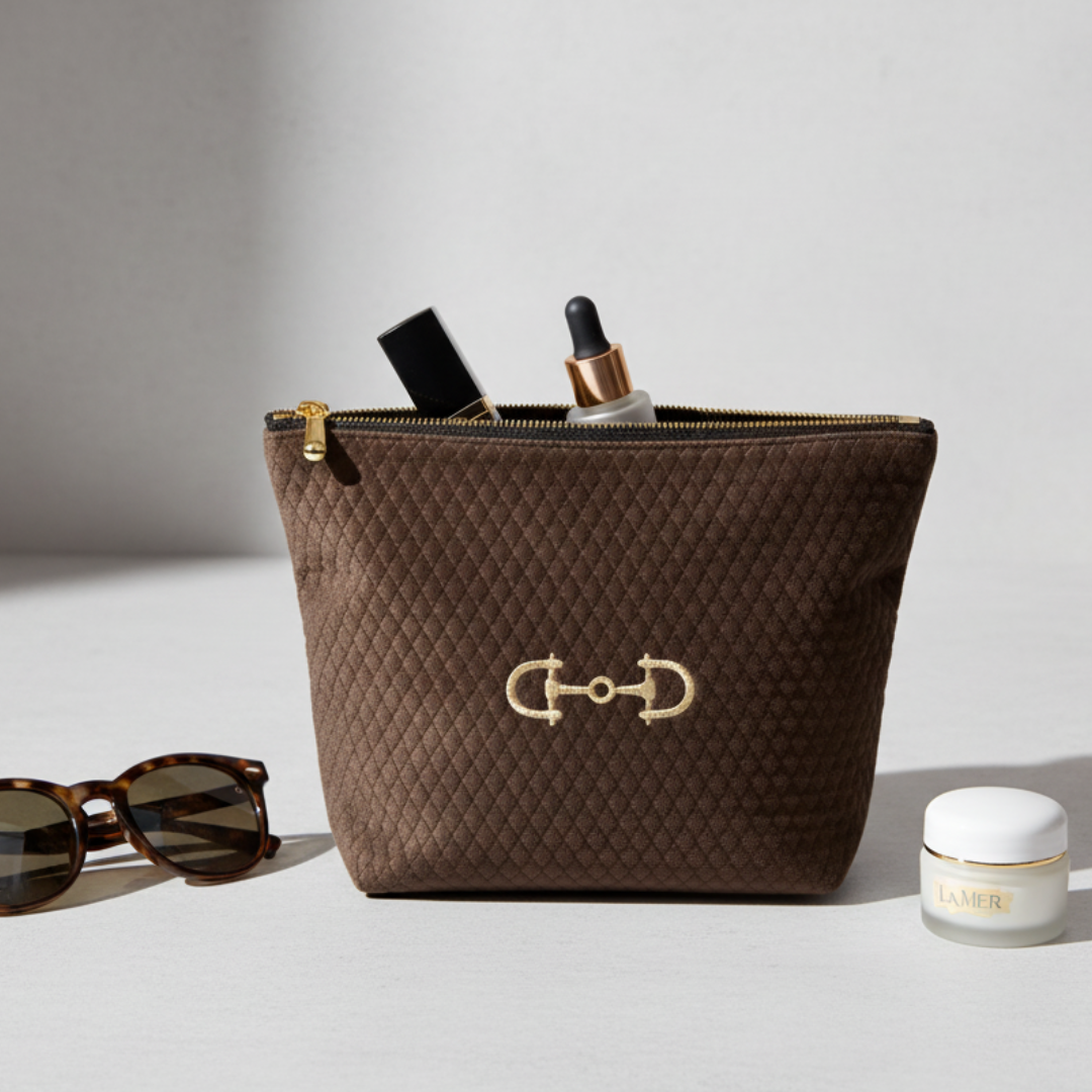 Brown quilted cosmetic bag with gold emblem on a light gray background