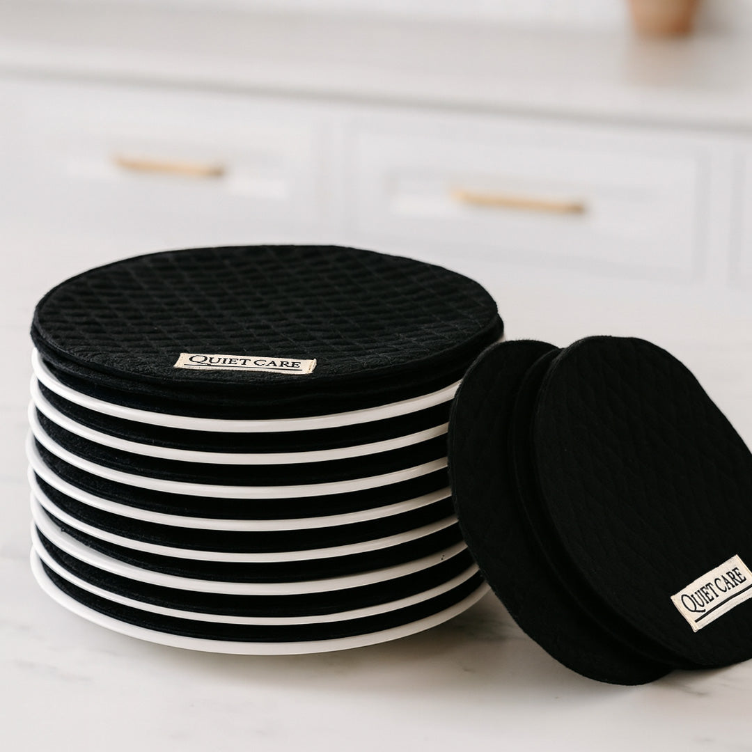 Stack of black and white Quiet Care earbud cases on a light surface.