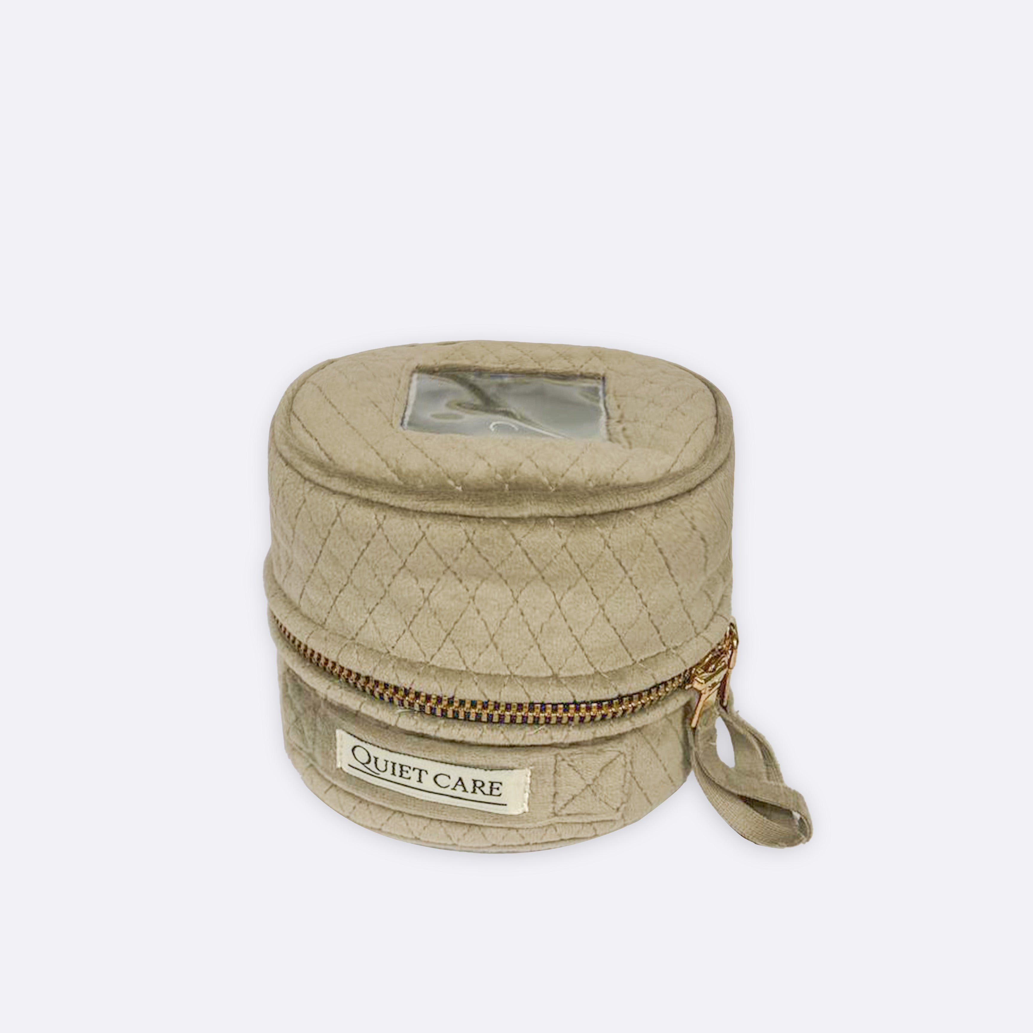 Quilted beige round bag with a gold zipper and 'Quiet Care' label on a white background