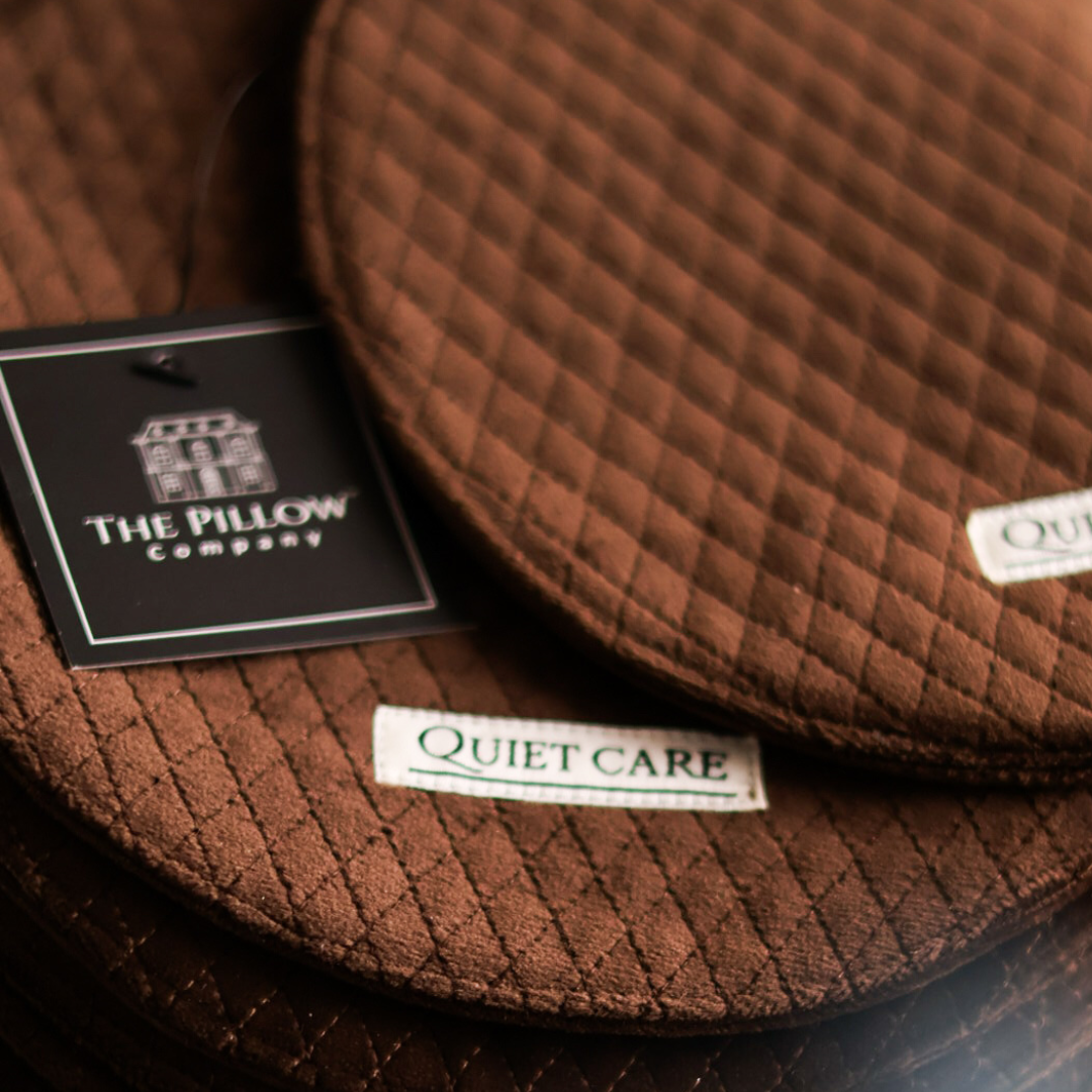 Brown quilted pillow with 'The Pillow Company' and 'Quiet Care' labels.