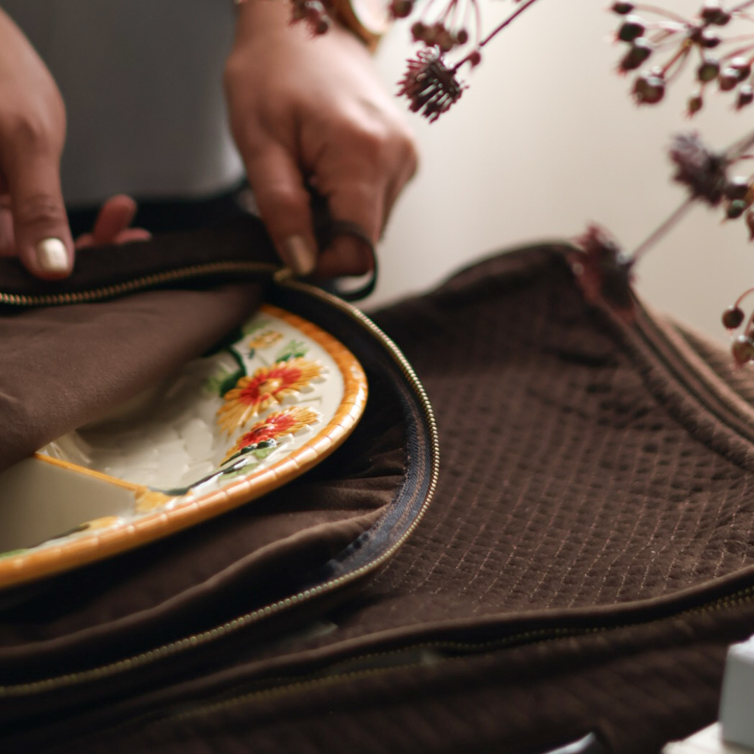Person opening a brown leather bag with a floral design on a white surface.