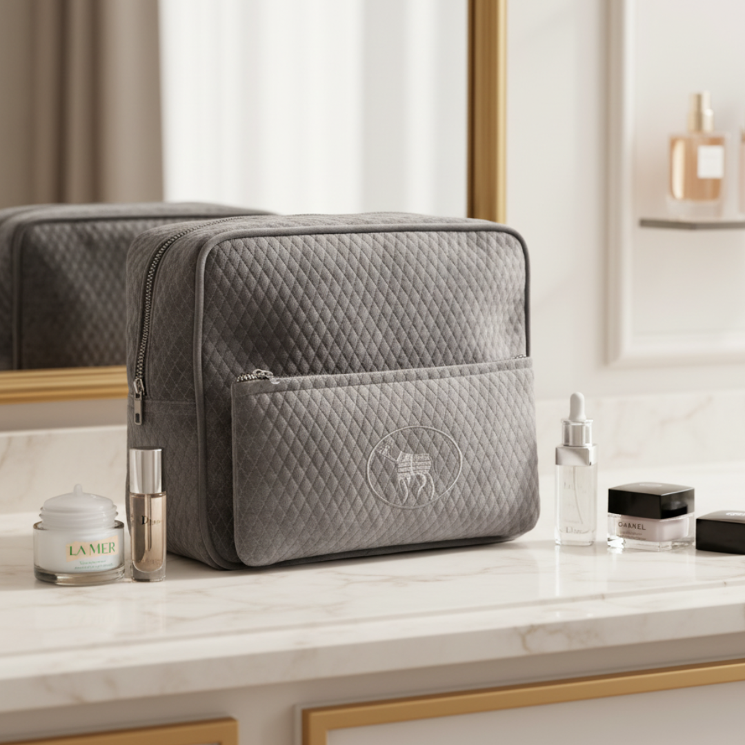 Gray quilted toiletry bag on a marble surface with skincare products in a bathroom setting