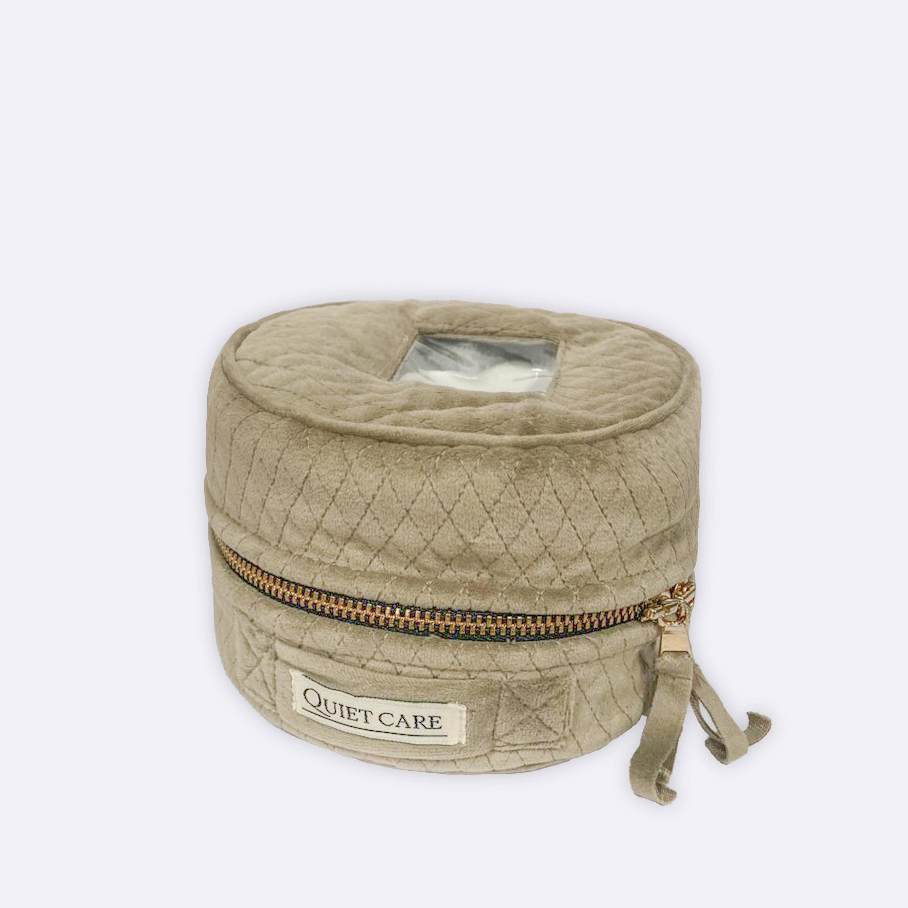 Quilted beige bag with a gold zipper on a white background, featuring the 'Quiet Care' brand.